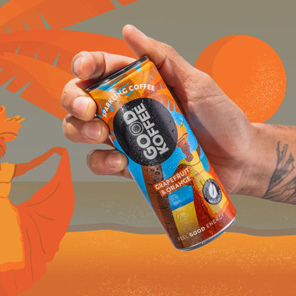 A hand holding a can of GOOD KOFFEE Sparkling Coffee in Grapefruit & Orange flavor, set against a stylized orange and gray background with tropical leaf silhouettes.