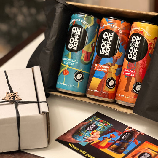 3 Cans in a white display box with a GOOD KOFFEE postcard sitting in front
